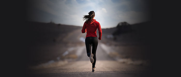 woman wearing a red top and black bottoms running on the road