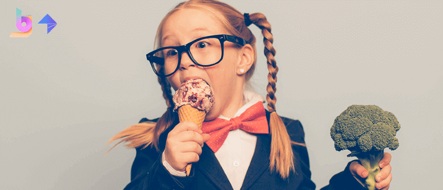 Picture of a little girl eating ice cream while holding a stem of broccoli in the other hand