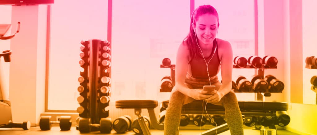 Personal trainer marketing on her phone in a gym