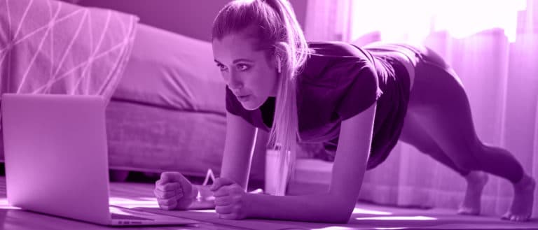 trainer doing a plank exercise and looking into a computer