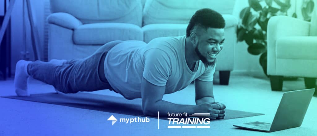 man smiling looking at a laptop while doing a plank in his home