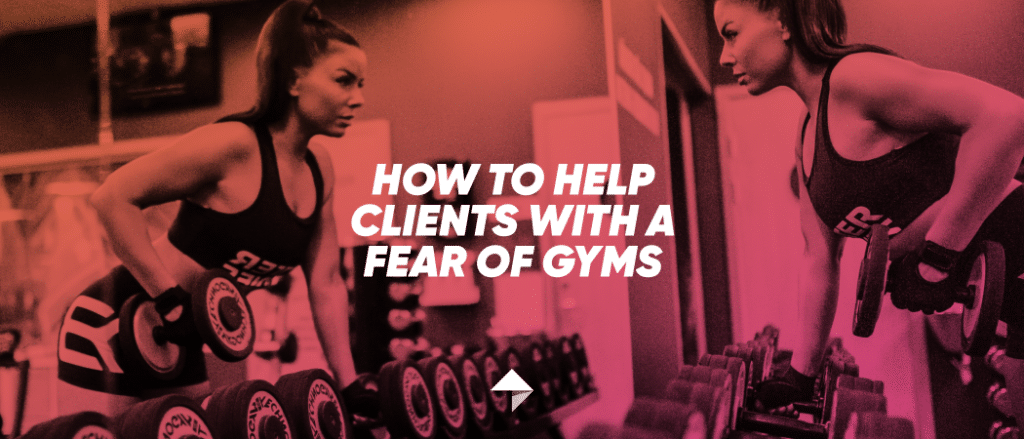 Strong woman picking up a dumbbell while looking at herself in the mirror