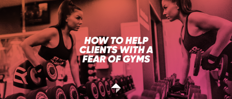 Strong woman picking up a dumbbell while looking at herself in the mirror