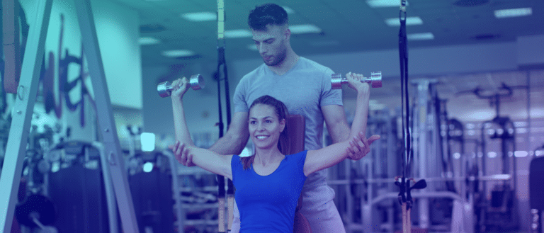 Personal trainer helping client lift dumbbells