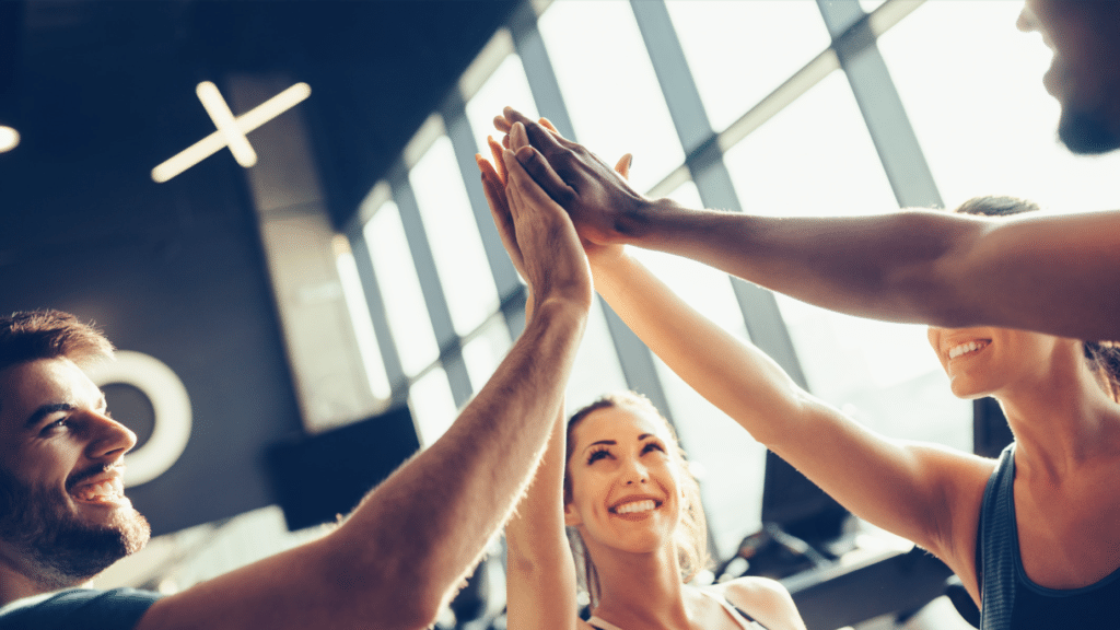 group of gym goers giving each other a high five and celebrating