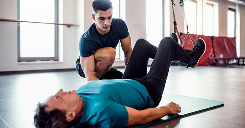 Trainer working out senior man in gym