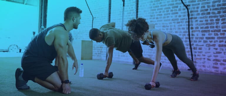 Trainer working out two clients in gym