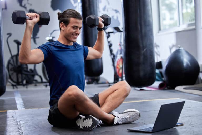 Man, laptop and bodybuilder online class in the gym for online personal training.