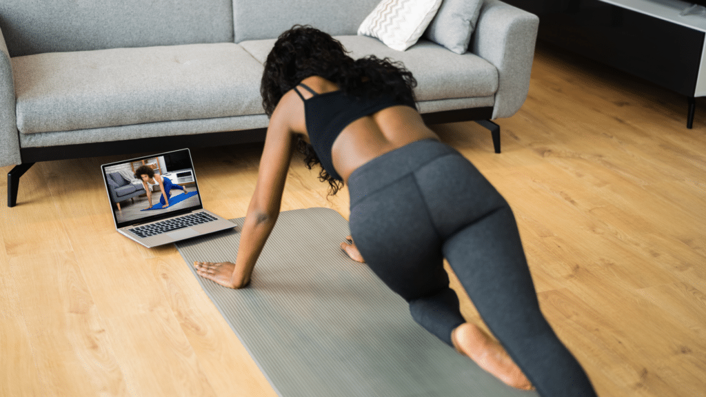 woman exercising while looking at a woman through laptop and following the woman's movements.