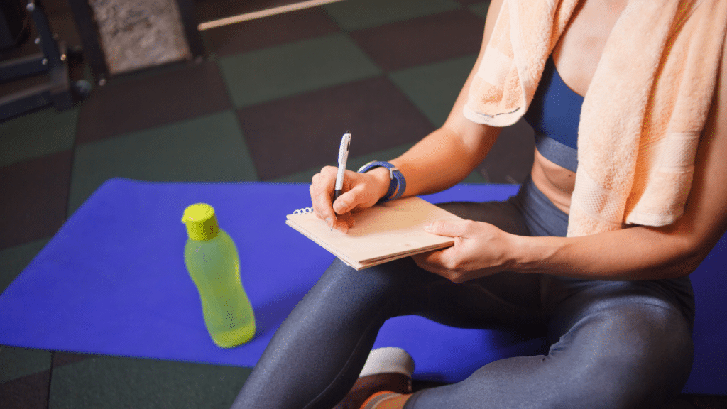 woman in gym writing out a plan in a notebook