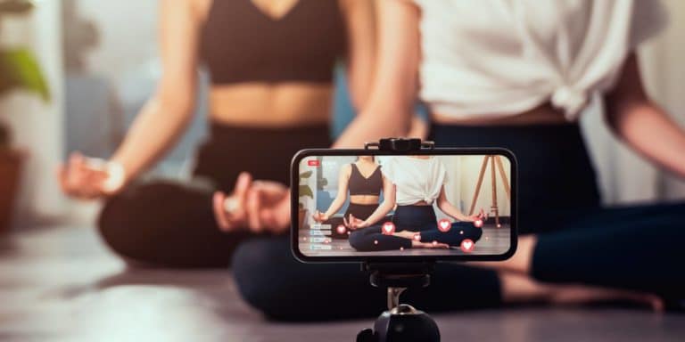 two fit women doing yoga and recording themselves on a live stream