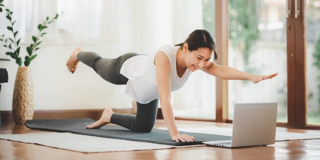 woman working out online from home with laptop