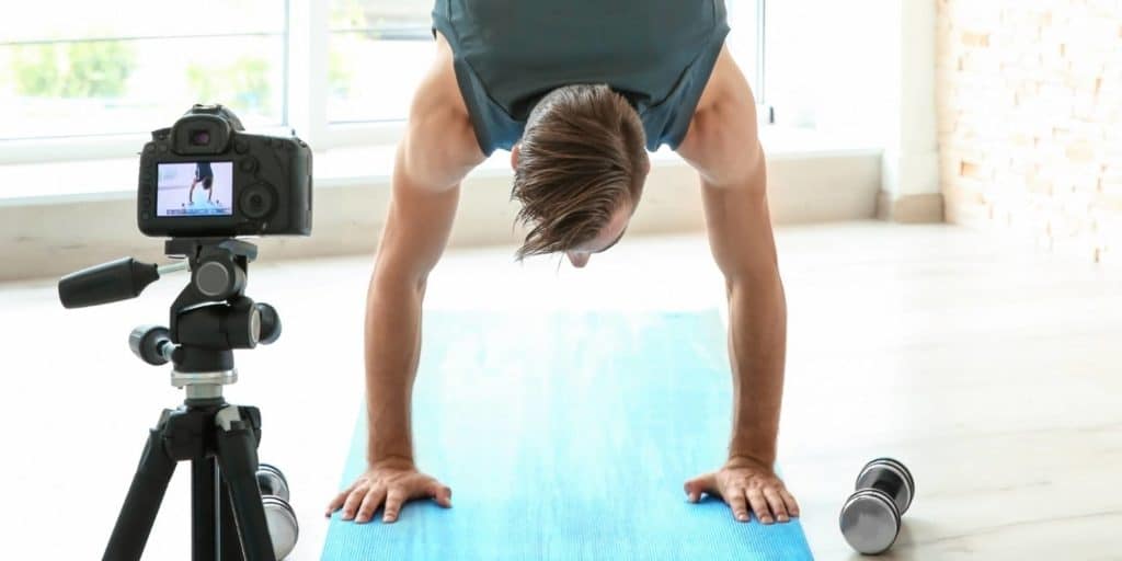 Man doing handstand and filming his workout on camera